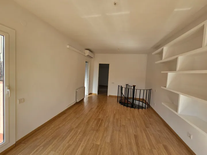 Buhardilla terminada: estanterías empotradas, suelo laminado y escalera de caracol